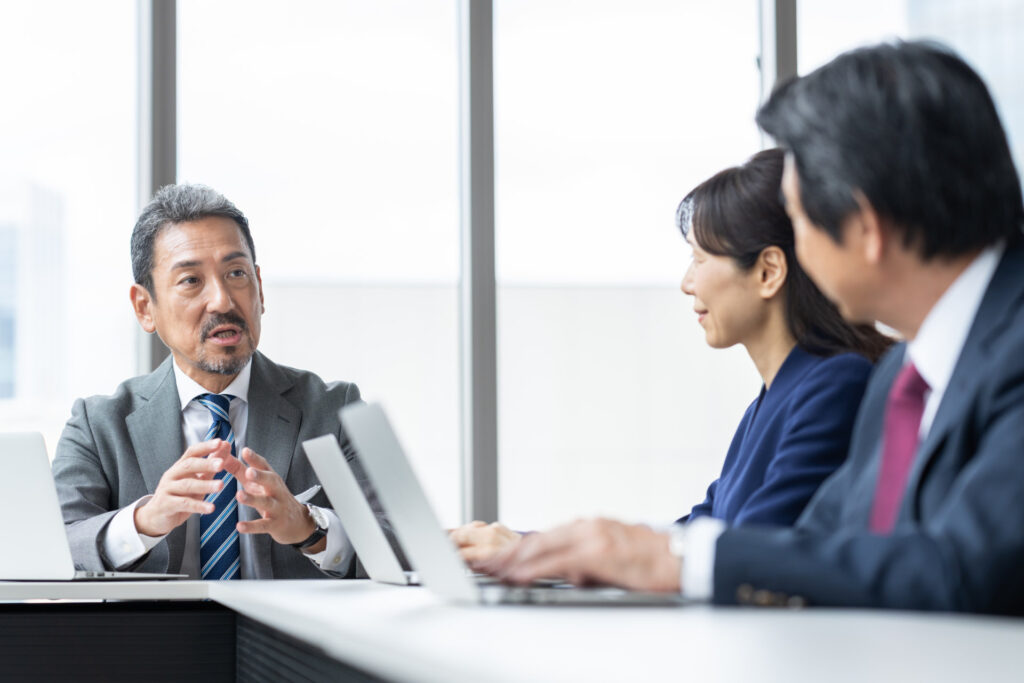会議室で打ち合わせる3人のビジネスパーソン