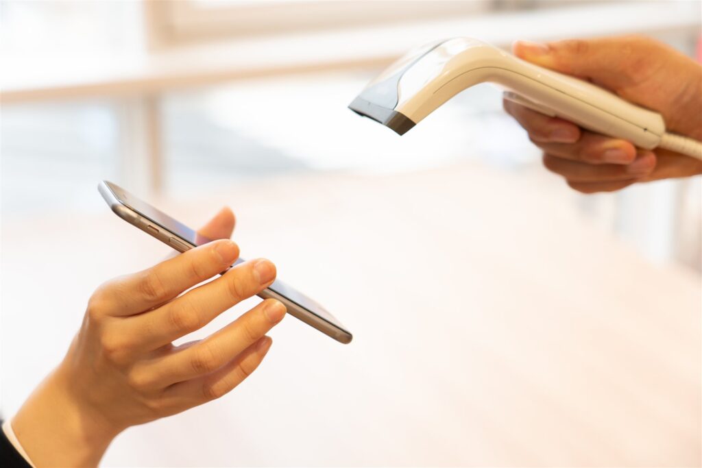 スマートフォンを読み取り機にかざす手元