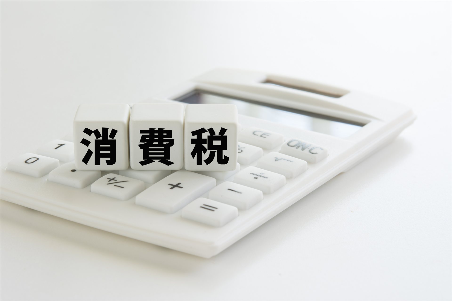 電卓の上に置いた「消費税」の文字の積み木