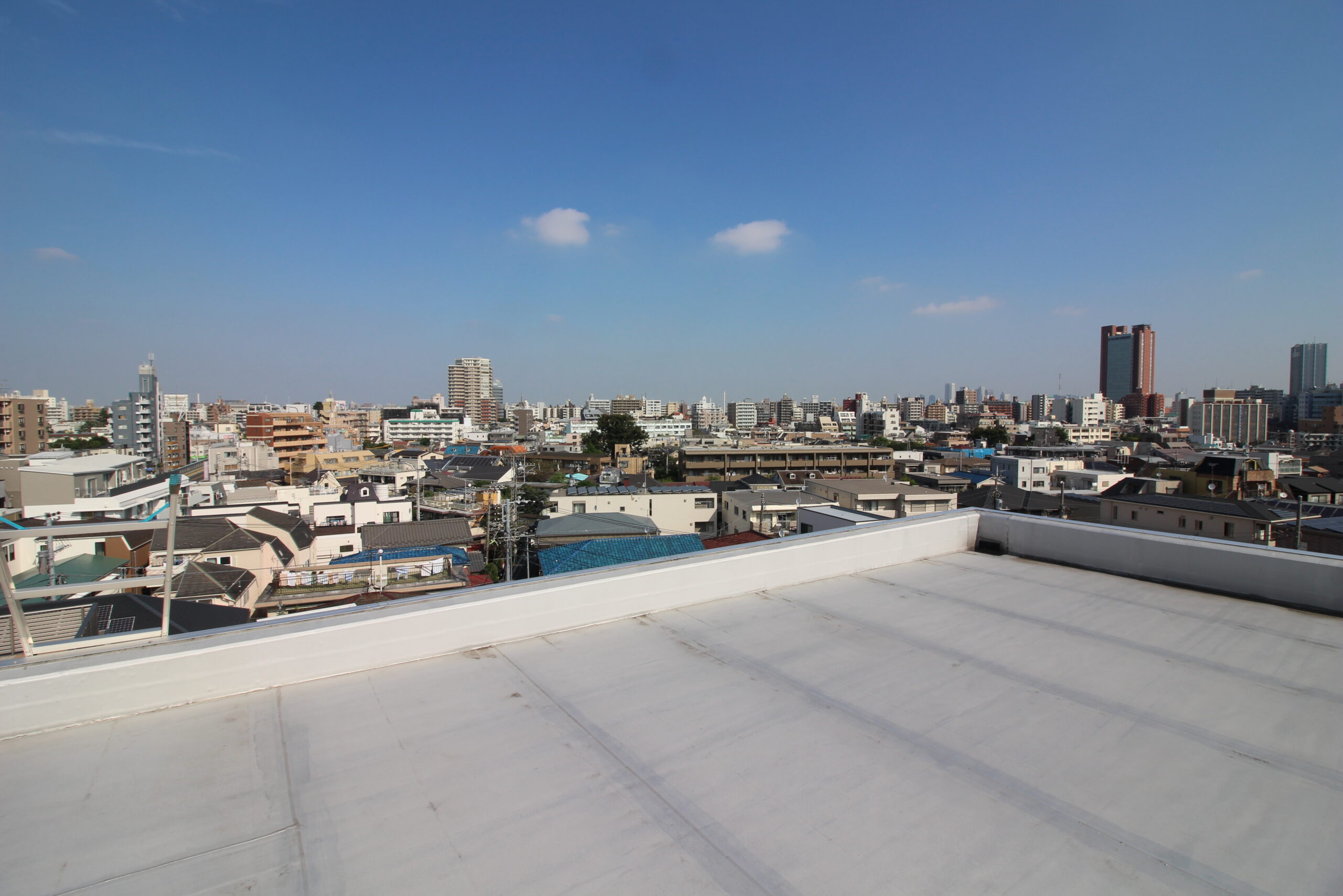 防水を仕上げた屋上と向こうに広がる住宅街