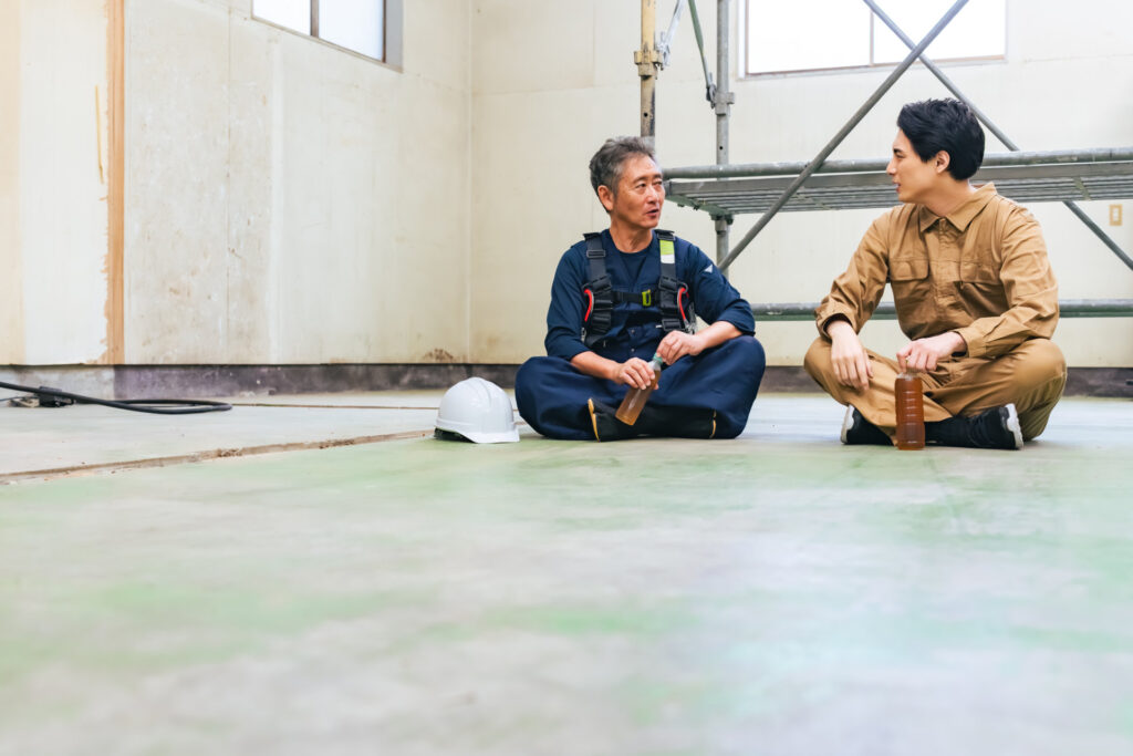 改装中の室内の床に座って話す職人2人