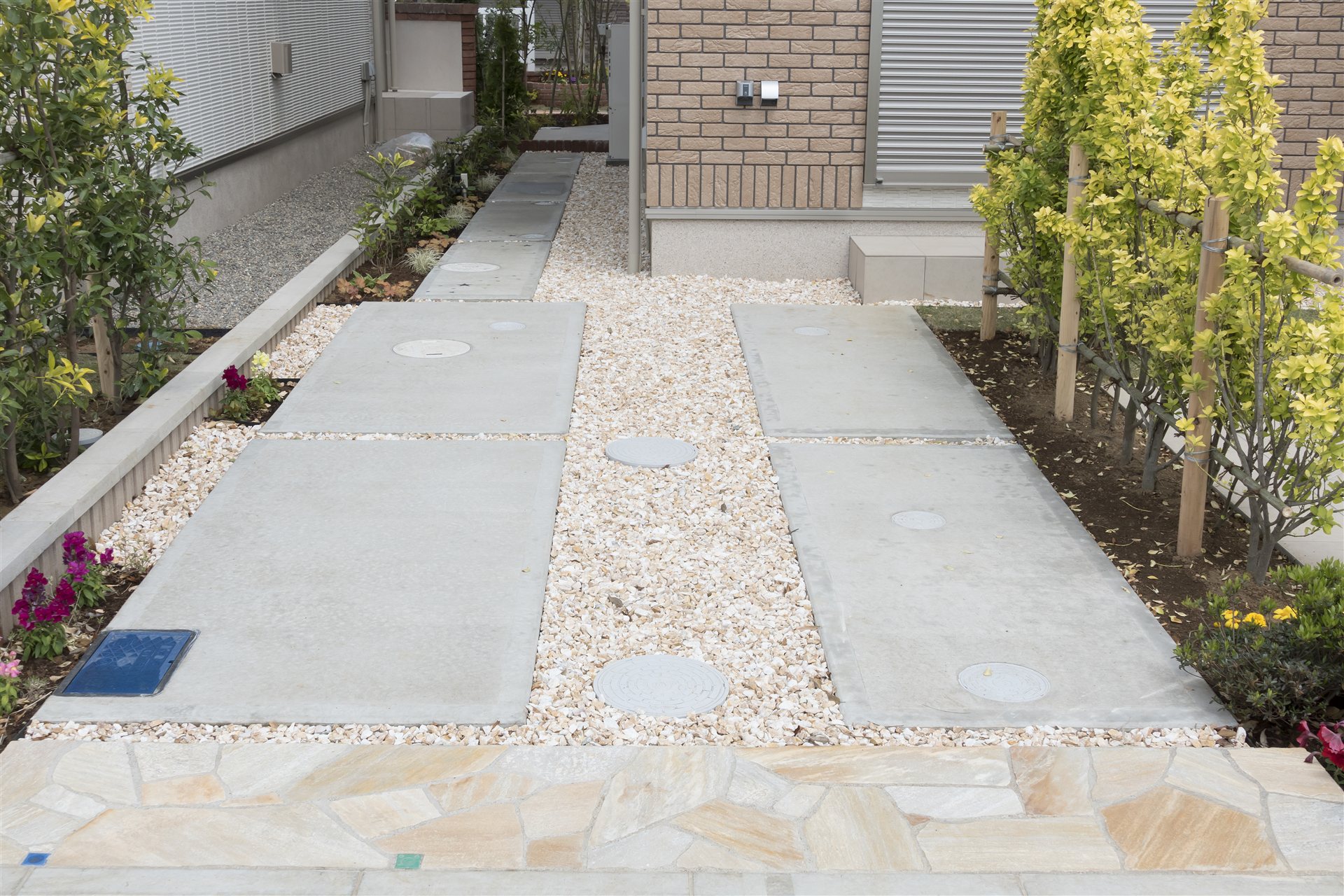 石を敷いた戸建て住宅の駐車場と植栽の外構