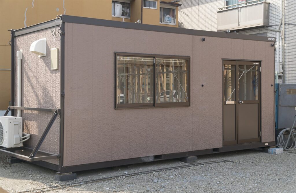 住宅街の空き地に置かれたプレハブの事務所棟