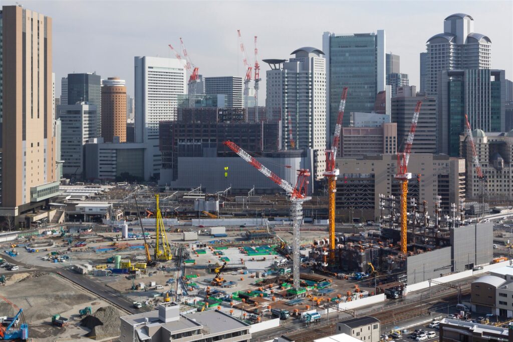高層ビル群の手前の再開発の建設現場とクレーン