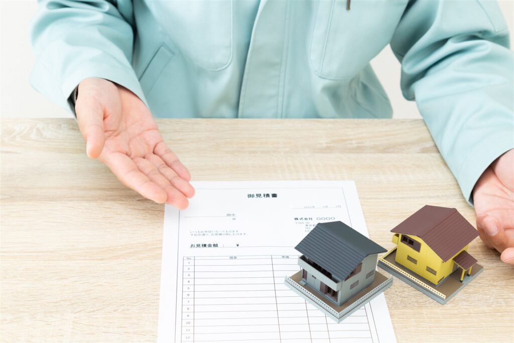見積書と家の模型を前に説明する作業着の人