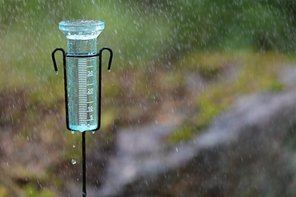 雨の降る庭に立つ雨量計