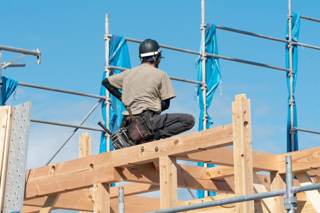 木造住宅の梁の上で作業する大工の後ろ姿