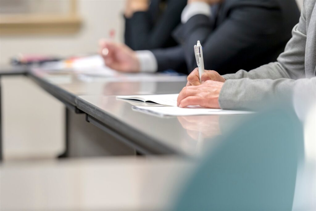 会議の机で書類にペンでメモを取る手元