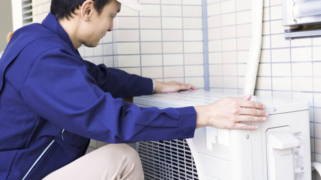 作業員が住宅のエアコン室外機を据え付ける様子