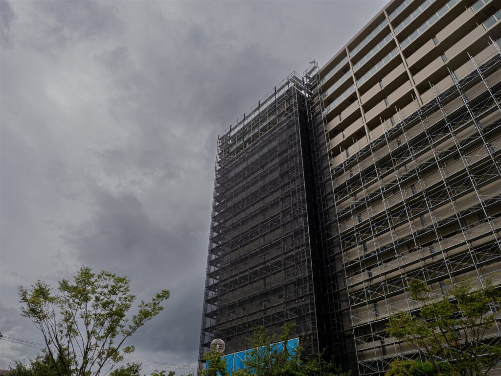 曇り空と足場の掛かった高層の集合住宅