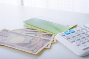机に並べた一万円札と通帳と電卓