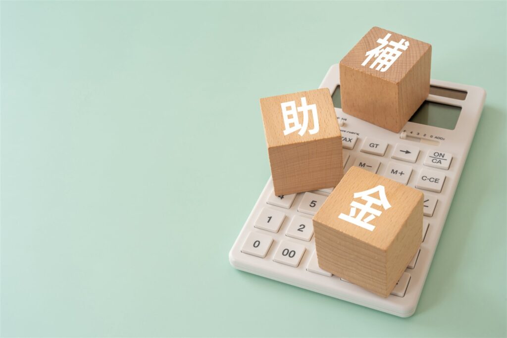 電卓の上に置いた「補助金」の文字の積み木