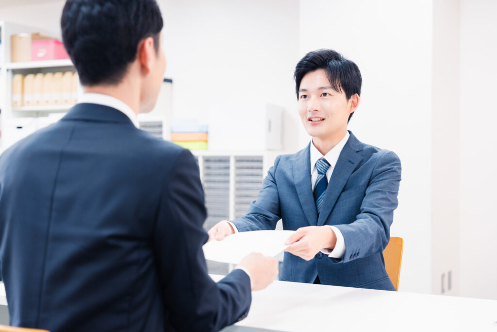 窓口で男性が書面を受け渡しする様子