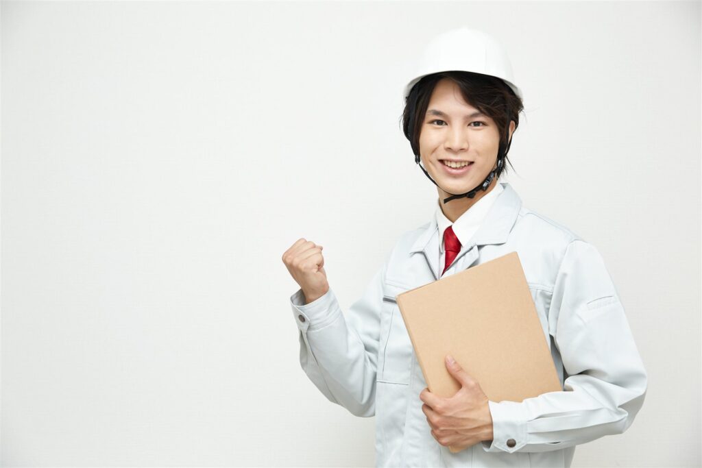ヘルメットに作業着でファイルを持つ男性