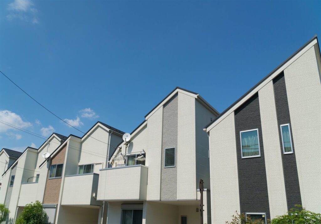 青空の下に並ぶ白と灰色の3階建ての住宅