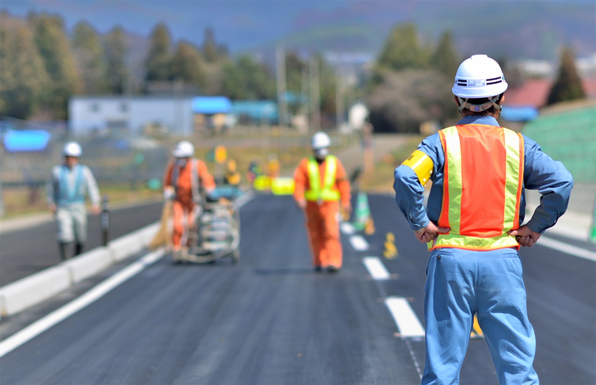 道路の工事現場を見渡す作業員の後ろ姿