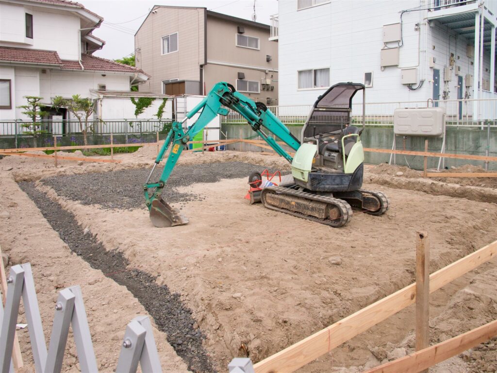 住宅街の更地で地面を掘る小型の油圧ショベル
