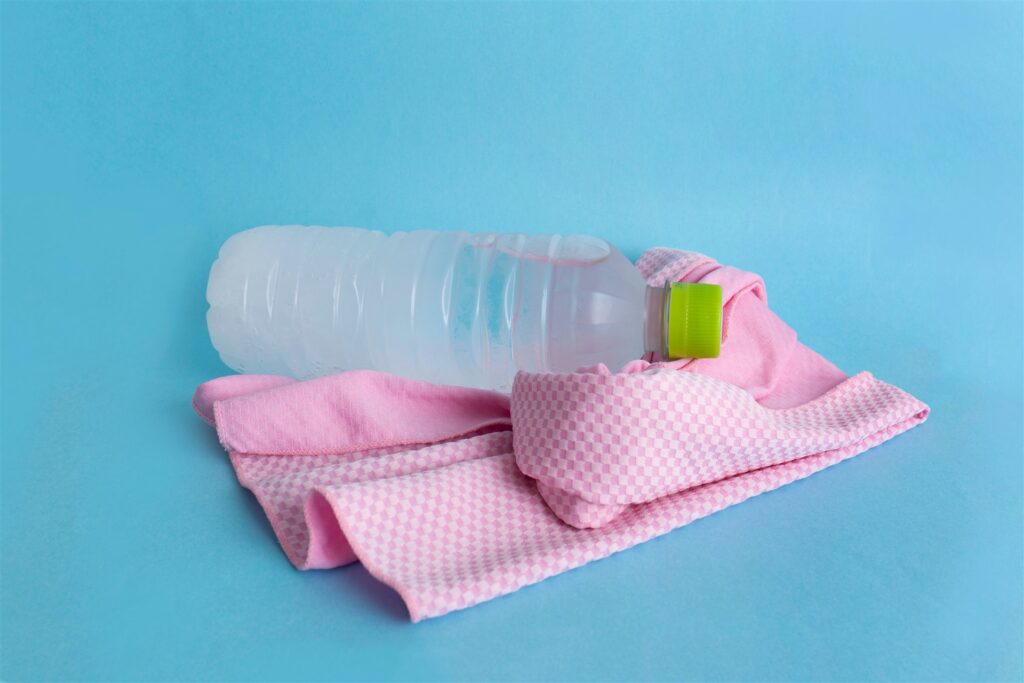 ピンクの冷感タオルと水のペットボトル