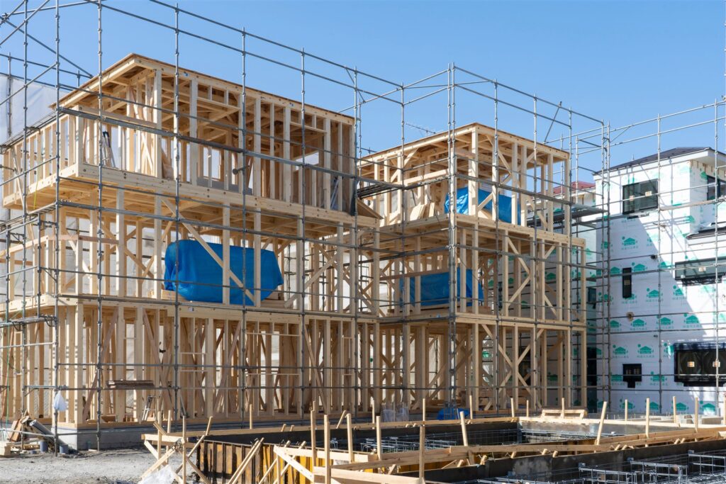 足場に囲まれた建築中の木造住宅の骨組み