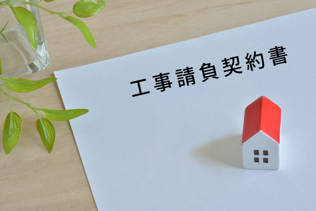 「工事請負契約書」と書かれた紙と家の模型