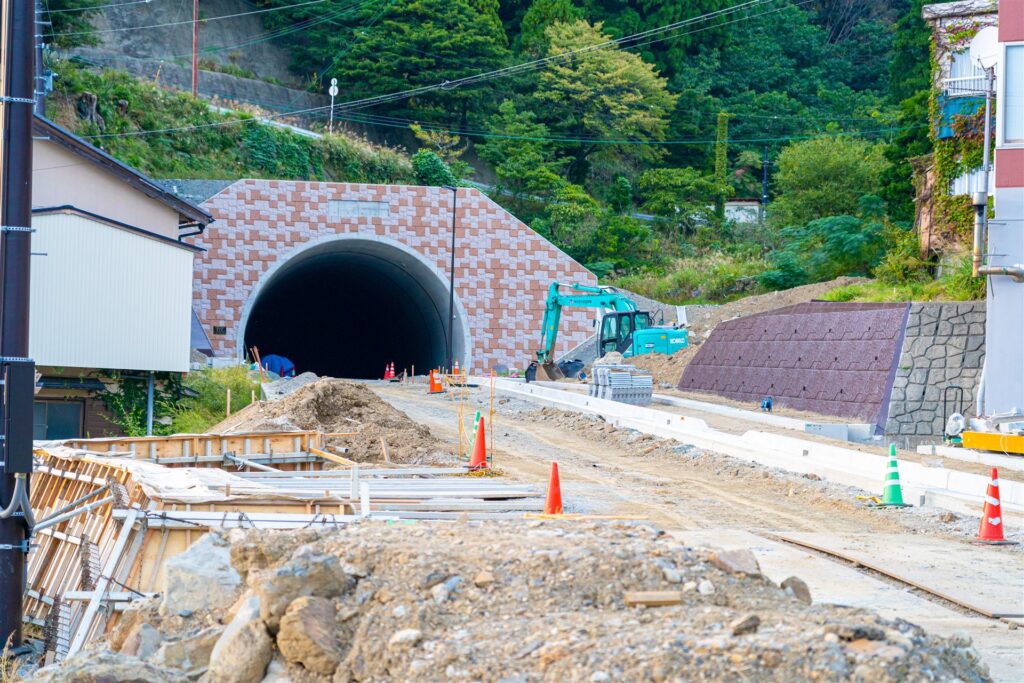 トンネルの入口と道路工事中の現場と重機