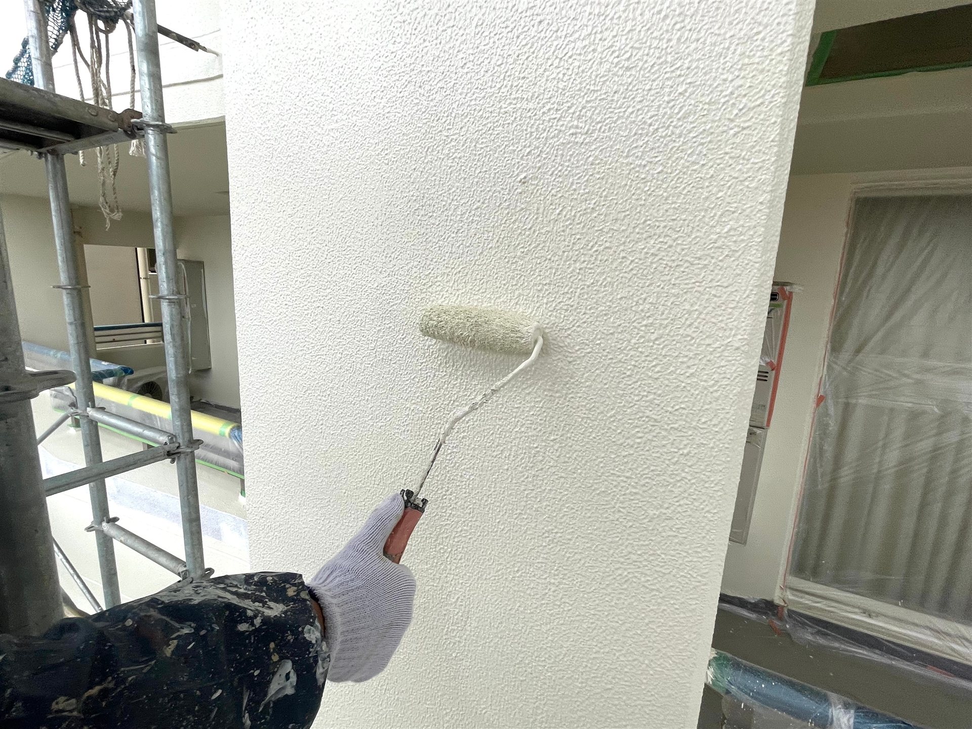 ローラーで外壁を塗装する職人の手元