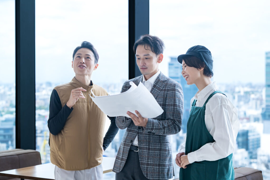 書類を囲んで打ち合わせをする3人