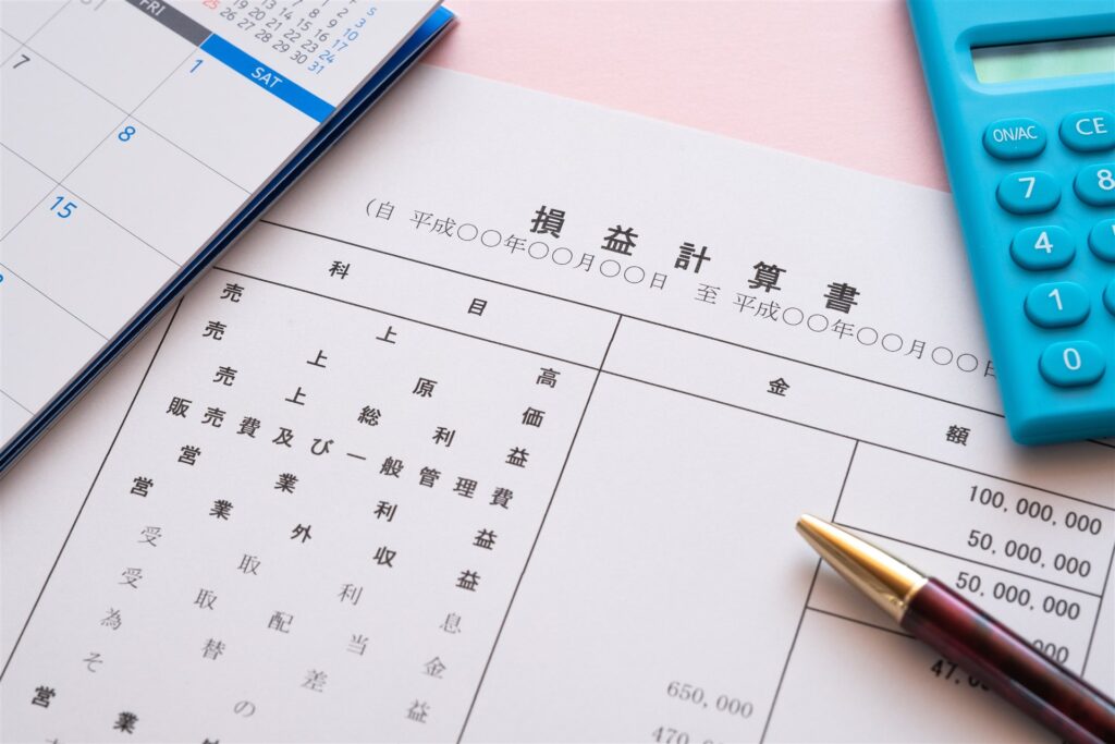 損益計算書とカレンダーと電卓とペン