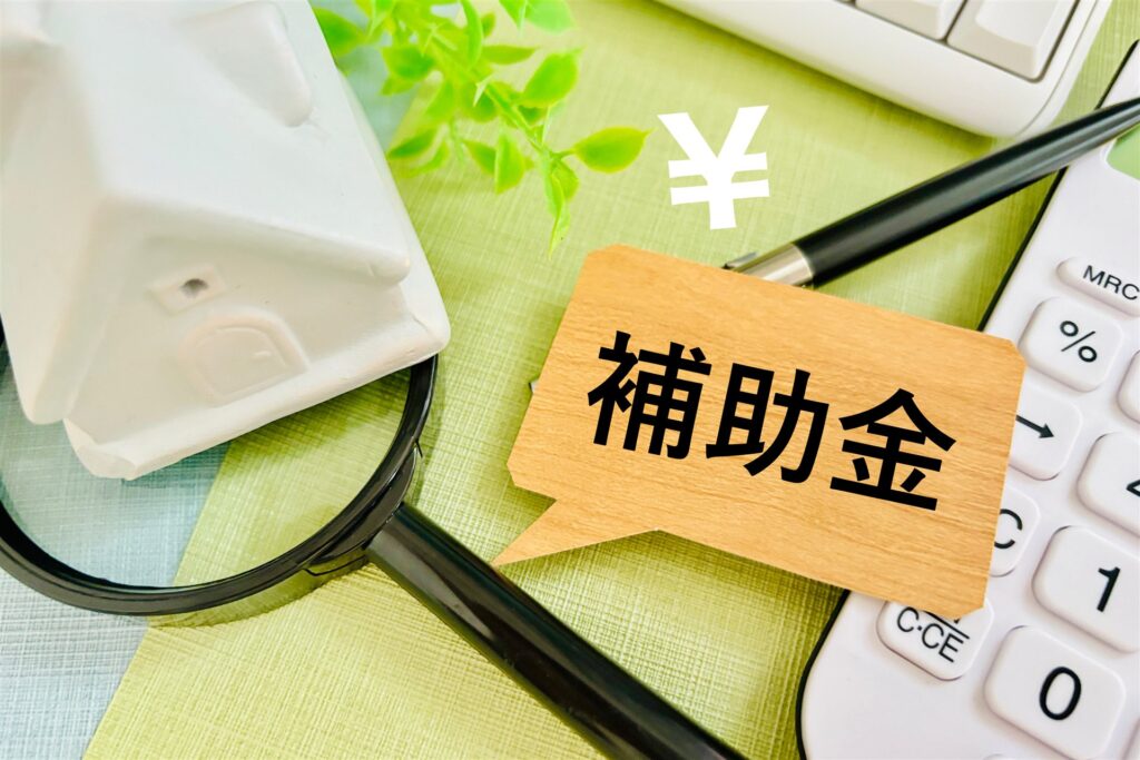 家の模型と電卓のそばに置いた「補助金」の札