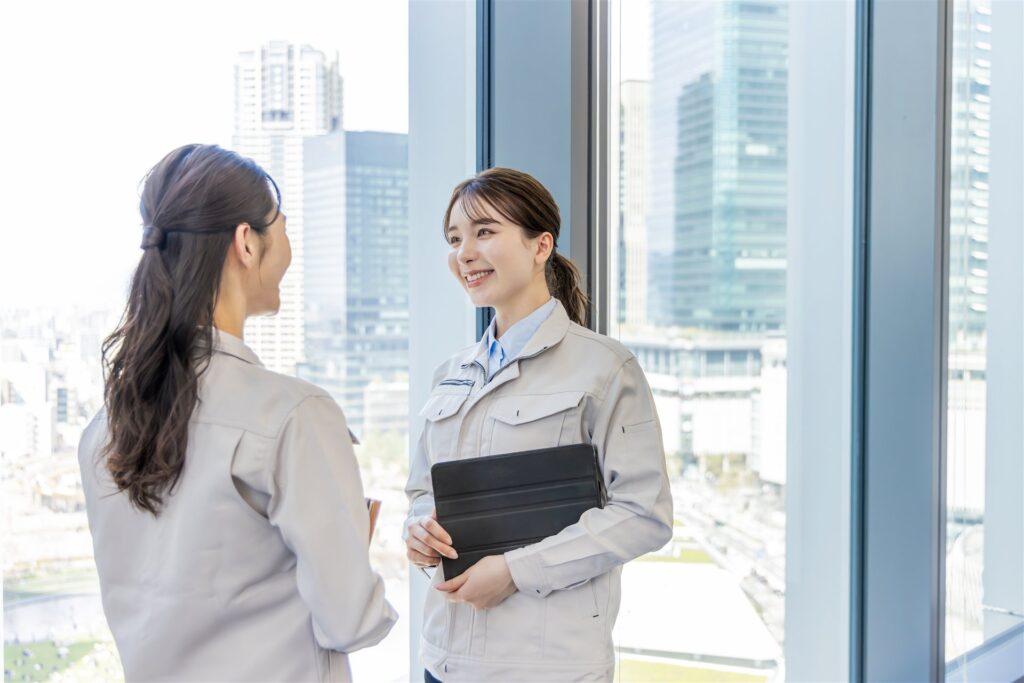 窓辺で話す作業服の女性2人