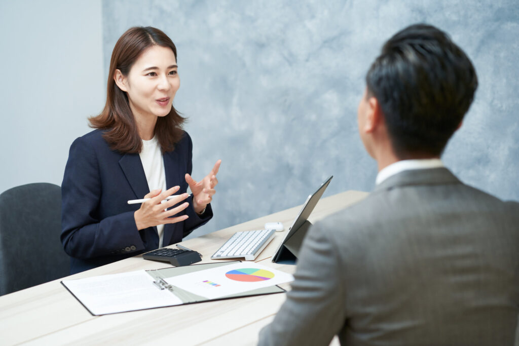 事務所で相談員が書類とグラフを見せて説明する様子