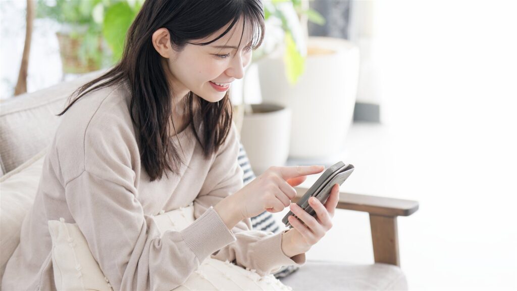 リビングのソファでスマートフォンを操作する女性
