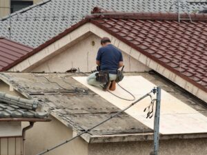 屋根の上で下地の板を張る職人の後ろ姿