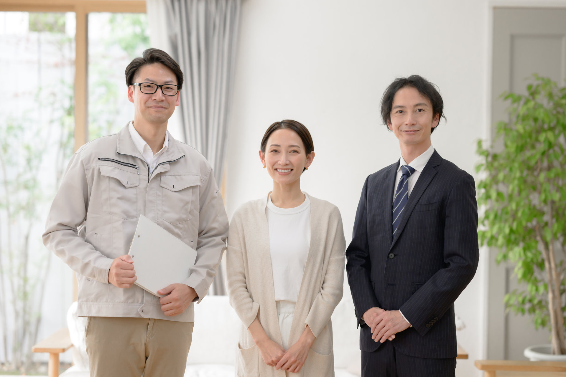 明るい住まいに並ぶ職人と住まいの人と担当者