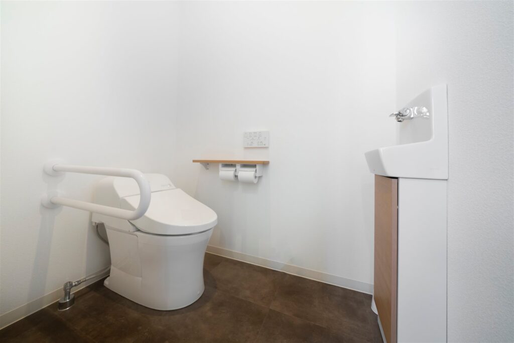 洋式トイレの横の壁に付けた跳ね上げ式の手すり
