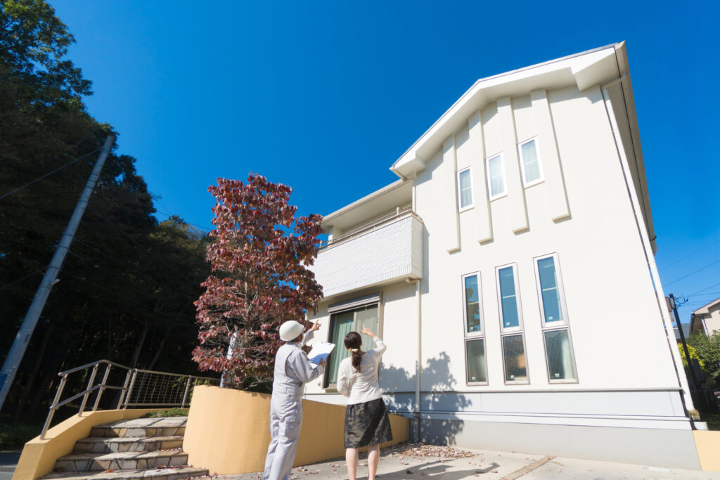 住宅の前で家を見上げる施主と作業服の人