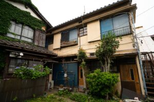 ツタが壁を覆う古い木造の家が並ぶ住宅の外観