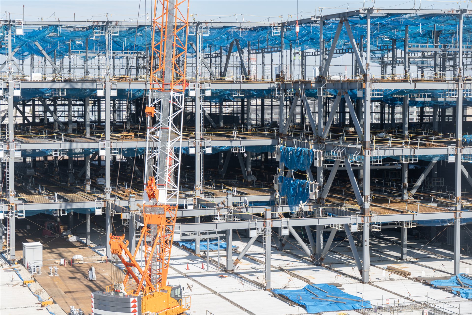 クレーンが立つ鉄骨造の建物の建方の現場