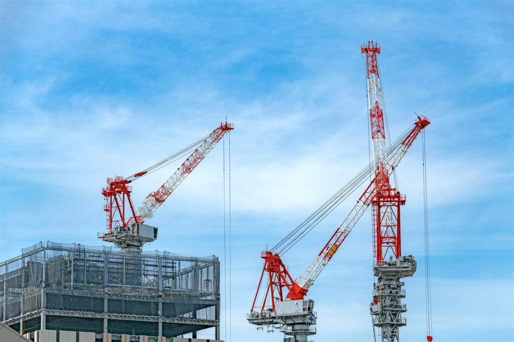 青空の下のクレーンと建物の骨組み