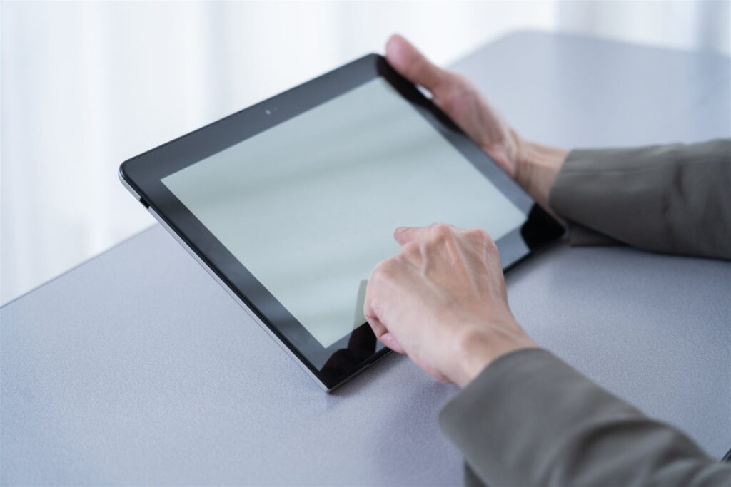 机の上のタブレットの画面に触れる手元