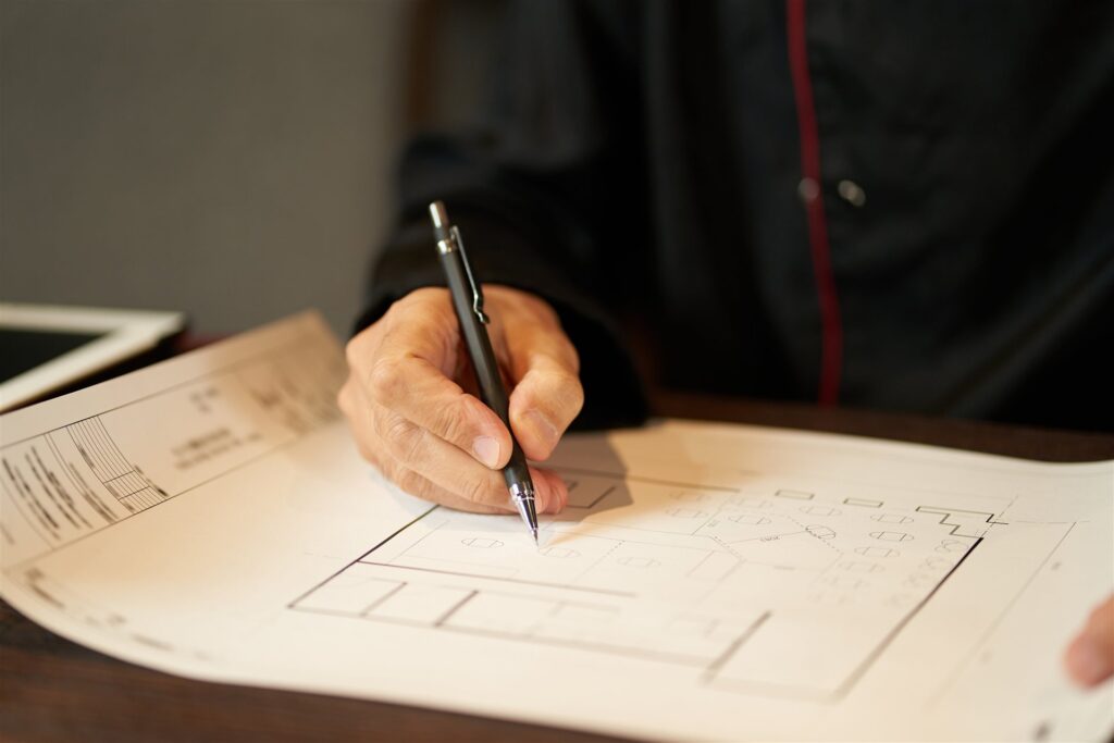 間取りの図面に鉛筆で書き込む手元