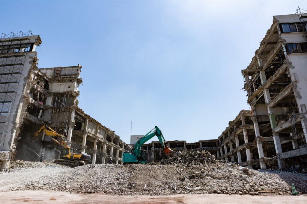 大きな建物の解体を進める重機2台とがれきの山