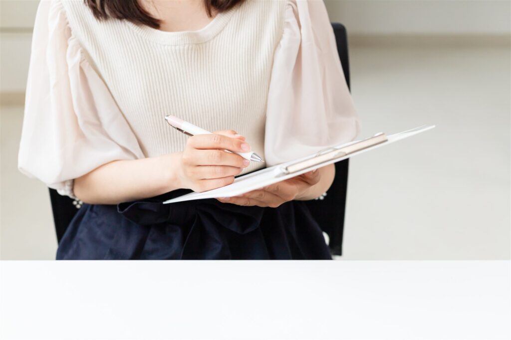 クリップボードの書類にペンで書き込む手元