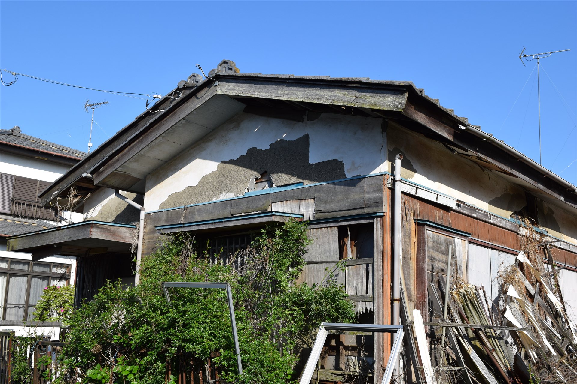 壁の塗りがはがれ板が崩れかけた古い木造の空き家