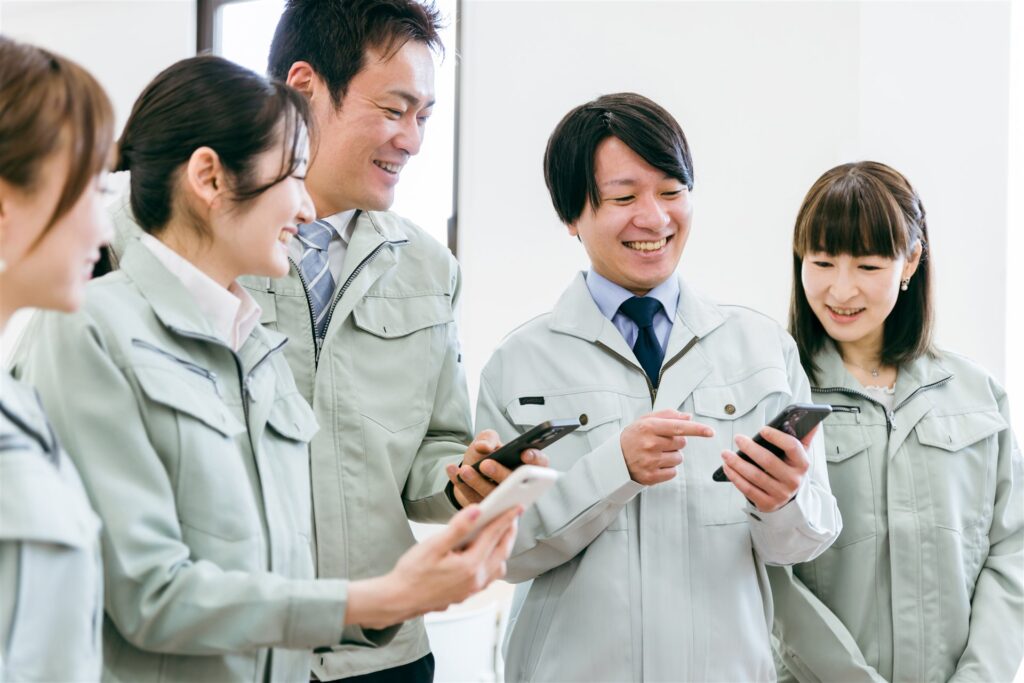 スマホを見て話す作業着の人たち