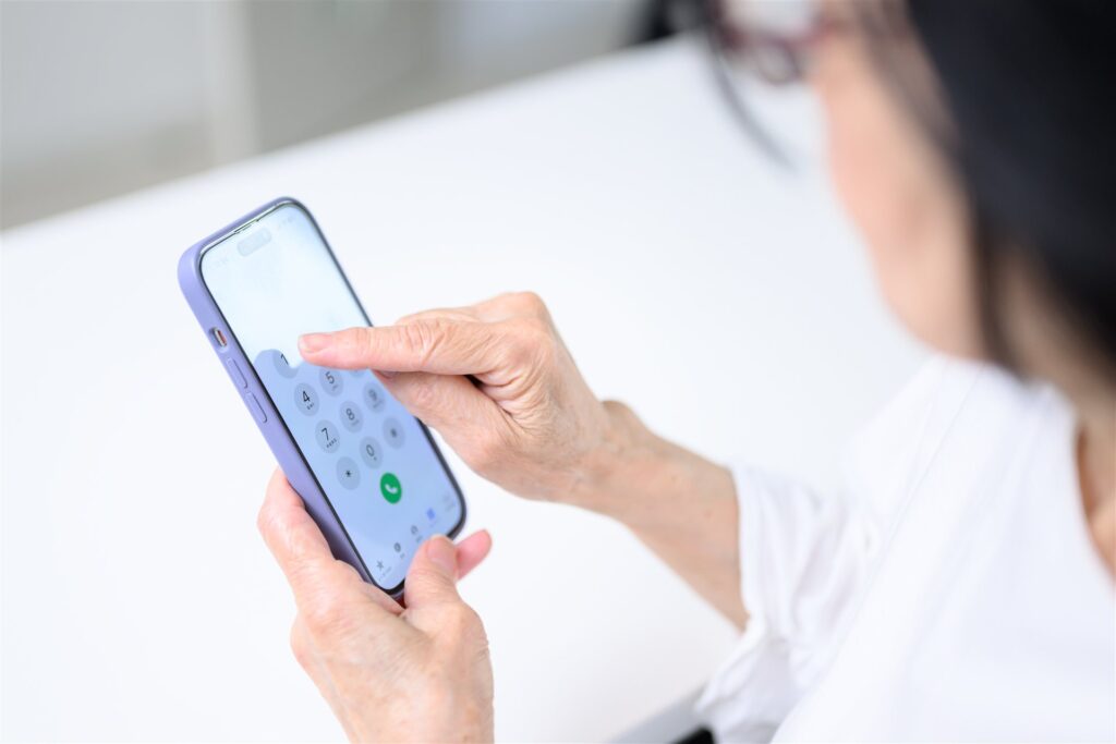スマートフォンで電話番号を押す人の手元