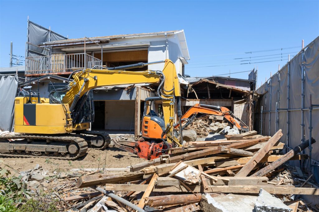 重機2台で2階建ての家を取り壊している現場