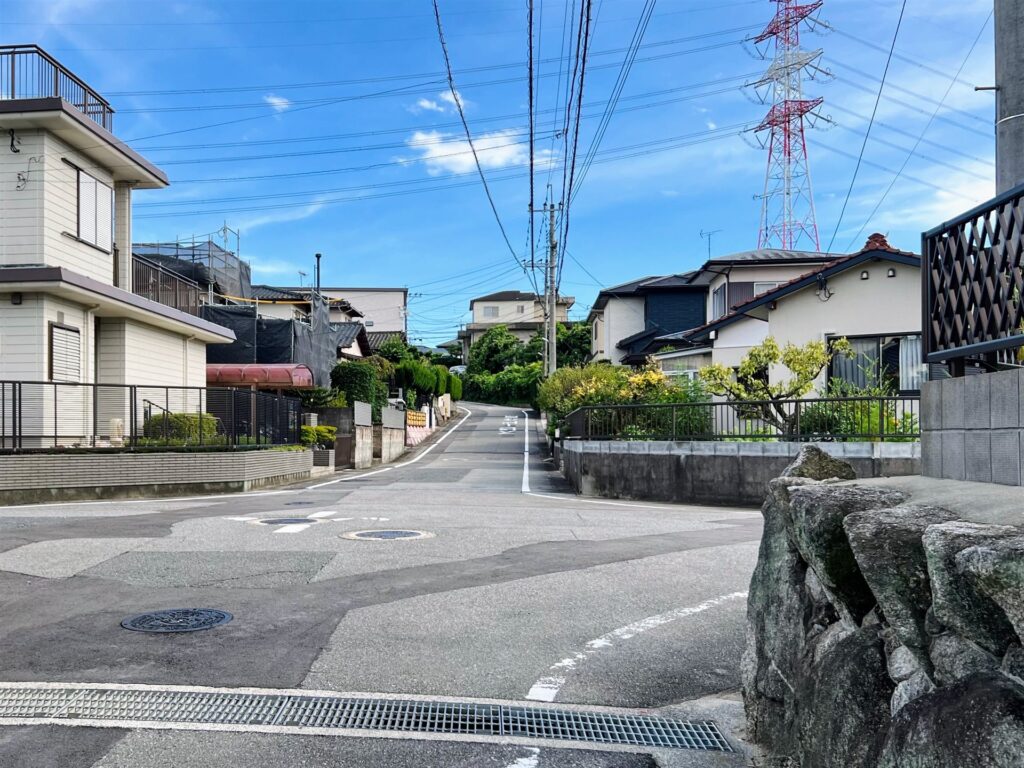 晴れた日の住宅街の坂道と道沿いに並ぶ一戸建て