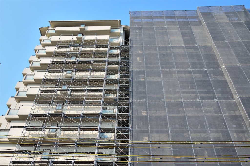 足場とネットで覆われた改修中のマンション
