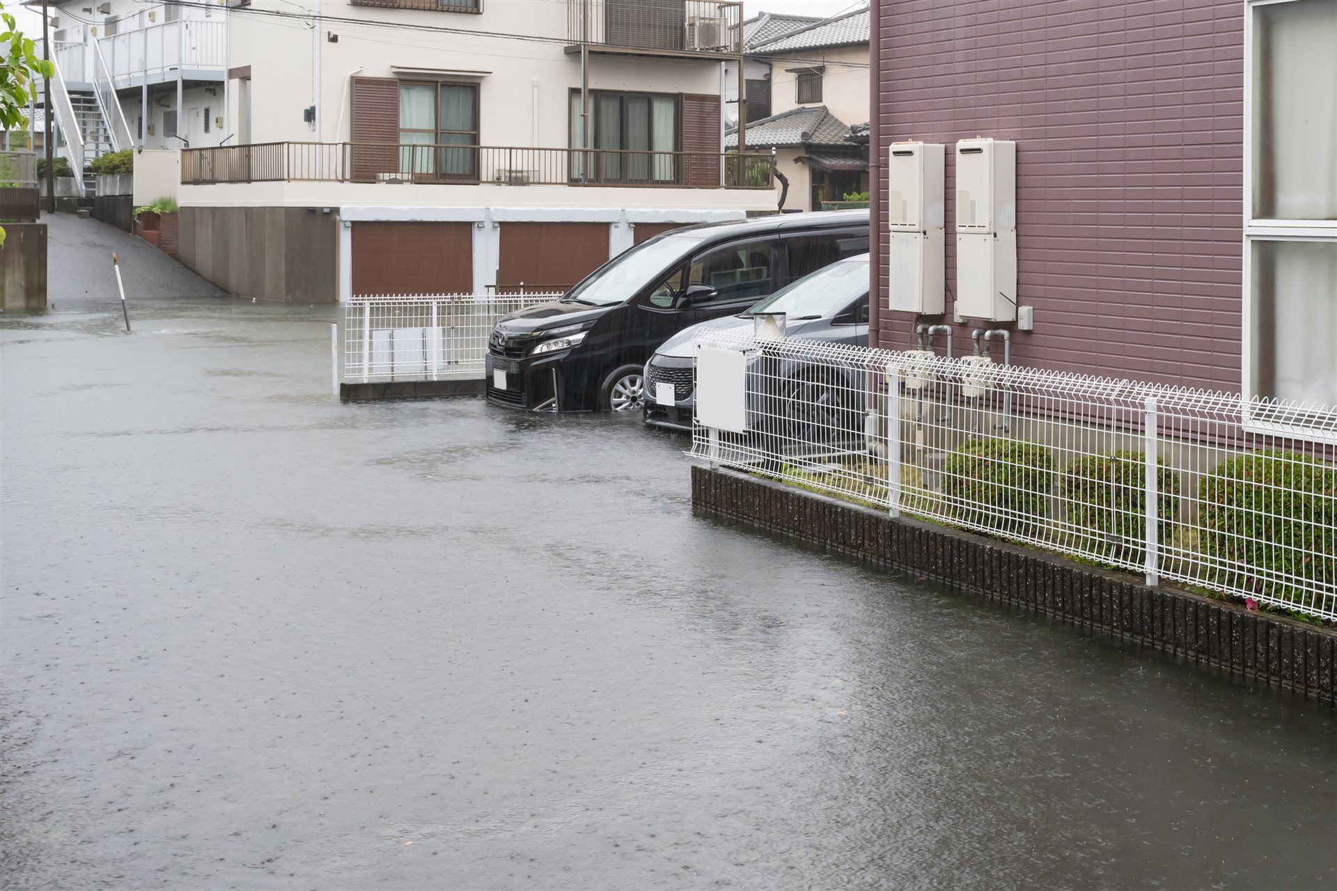 雨で冠水した住宅街の道路と駐車中の車